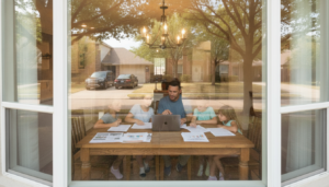 A young family reviewing paperwork at their kitchen table while researching insurance discounts Dallas Fort Worth homeowners can qualify for
